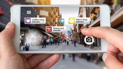Eine Hand hält ein Smartphone auf der sich Informationen über Restaurants und Cafés in der Umgebung befinden