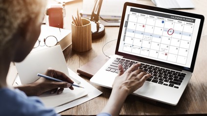 Frau organisiert ihre Termine in einem Kalender am Laptop