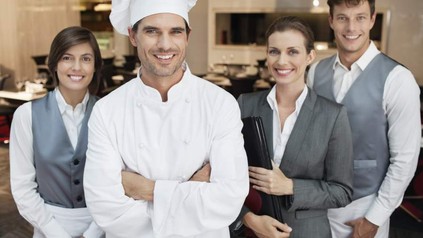 Ein Koch, zwei Servicekräfte und eine Führungskraft im Restaurant