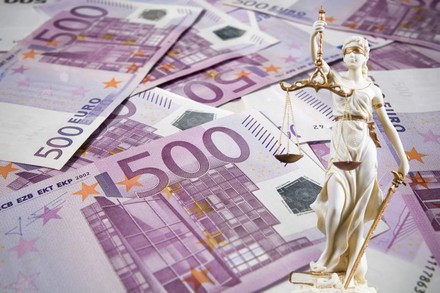 Eine Justitia Statue steht vor mehreren 500€ Scheinen