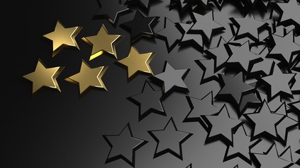 Ein goldener Stern unter vielen schwarzen Sternen