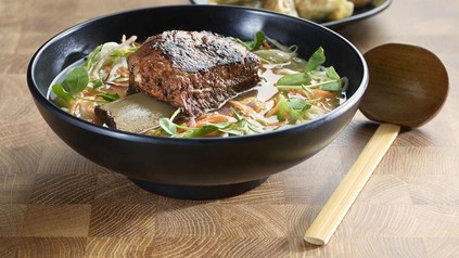 Eine Schüssel Ramen auf einem Holztisch mit einem Holzlöffel