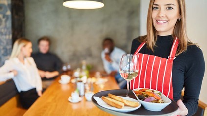 Aushilfe im Restaurant bringt Essen auf dem Tablet an die Tisch
