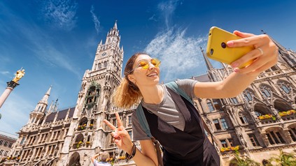 Tourist in München macht ein Selfie mit dem Smartphone.