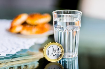 Ein Glas Wasser und ein Null-Euro-Stück daneben