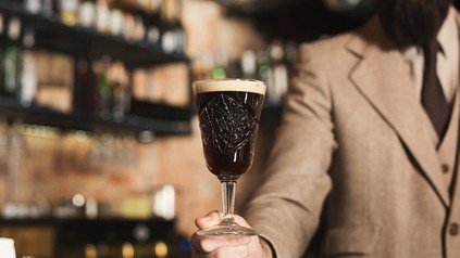 Ein Herr im Anzug präsentiert ein Craft-Bier