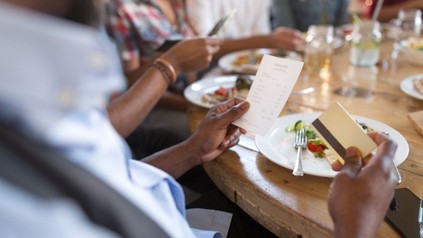 Mann an Esstisch möchte mit Karte bezahlen