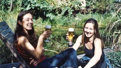 Zwei Frauen an einem Gewässer trinken Bier