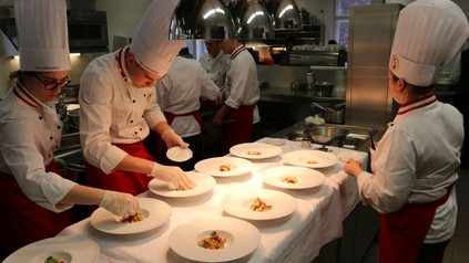 Junge Köche richten mehrere Gerichte auf Tellern an