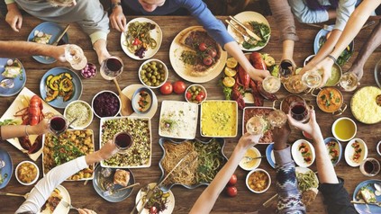 Gruppe sitzt gemeinsam an Esstisch und speist