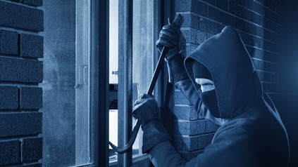 Maskierter Einbrecher bricht Fenster mit Brecheisen auf