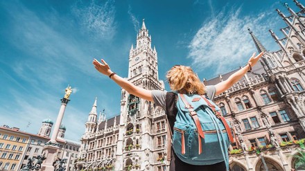 Touristin breitet die Arme auf dem Münchner Rathausplatz aus.