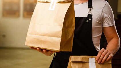 Lieferdienst Mitarbeiter trägt zwei gepackte Tüten mit Essen