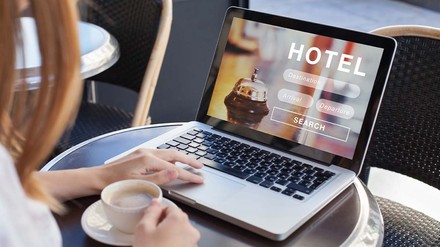Frau bucht im Kaffee ein Hotel auf dem Laptop