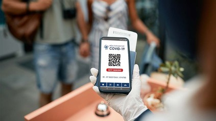 Rezeptionistin überprüft am Handy den Impfnachweis eines Gastes