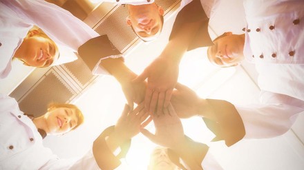 Mitarbeiter tuen ihre Hände in der Mitte zusammen