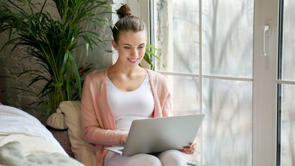 Frau sitzt bequem zu Hause mit ihrem Laptop