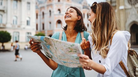 zwei junge Touristinnen stehen mit einer Stadtkarte auf einem Platz
