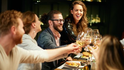 Freunde sitzen am Tisch und stoßen an