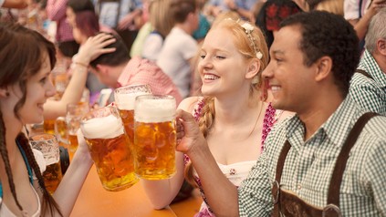 Buam und Madln stoßen im Festzelt mit einer Mass Bier an.