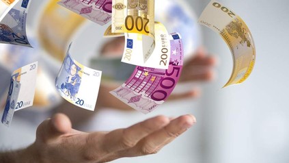 Zwei Hände jonglieren mit mehreren Geldscheinen