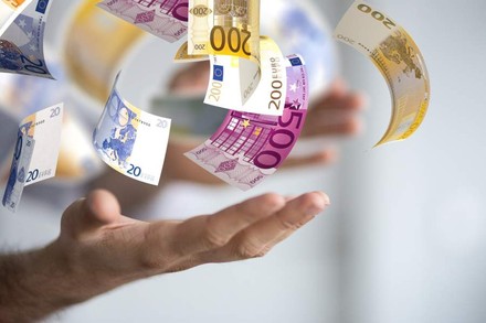 Zwei Hände jonglieren mit mehreren Geldscheinen