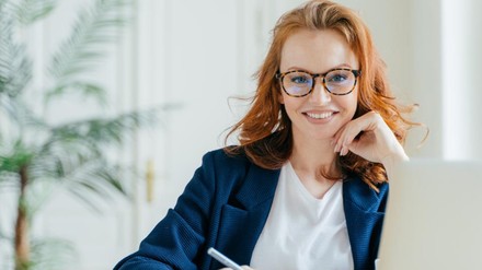 Rothaarige Frau lächelt in die Kamera.