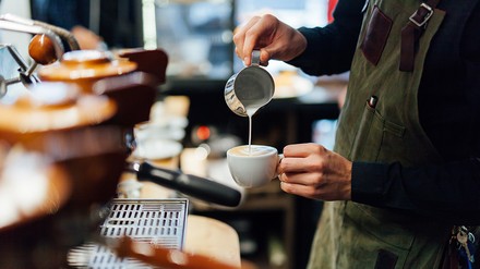 Barista schenkt Milch ein