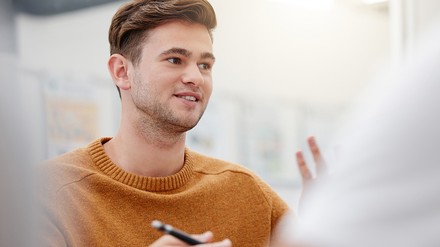 Ein junger Mann im Gespräch mit einer anderen Person.