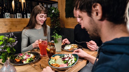 Drei Freunde sitzen an einem Tisch und jeder von ihnen isst eine gesunde Bowl.