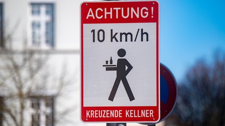 Ein Schild mit dem Schriftzug „Achtung! kreuzende Kellner“ steht in der Peenstraße am Marktplatz von Anklam. (Foto: © picture alliance/dpa | Stefan Sauer)