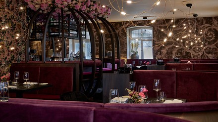 Florale Tapeten, mauvefarbene Samtbänke und aufwändig gestaltete Kunstblumen an der Decke kreieren eine hochwertige und glamouröse Kulisse. (Foto: © Annette Sandner)