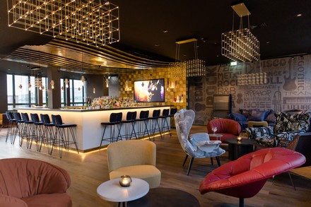 Bar- und Loungebereich im vierten Obergeschoss sind im Zeichen moderner Musikstile, von Hip-Hop, Rock bis Jazz gehalten. Die Bar ist der zentrale Blickfang und angelehnt an das Design einer Bühne, hinter der ein großer Monitor Ausschnitte von Konzerten zeigt. (Foto: © Motel One)