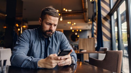 Gast in einem Restaurant schaut verärgert auf sein Handy.