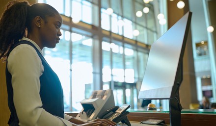 Mitarbeiterin an der Rezeption vor einem Computer