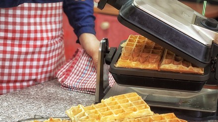 Eine Person bereitet Waffeln mit einem Waffeleisen zu.
