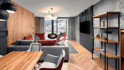 Großzügiger Wohnraum mit stylischem Kamin und Essbereich in der Top Suite Deluxe im Edelweiss Salzburg Mountain Resort .