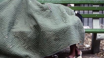 Obdachlose unter Decke auf Bank
