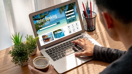 Mann bucht Hotel via Laptop