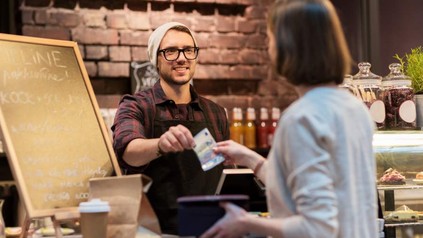 Eine Frau bezahlt in einem Café mit einem 20€ Schein