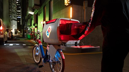 Lieferfahrer holt nachts Pizza aus dem neuen Delivery Bike von Domino's Pizza