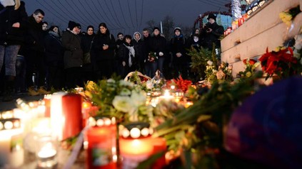 Trauernde Menschen vor Kerzen