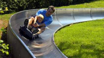 Mann mit Kind auf Sommerrodelbahn