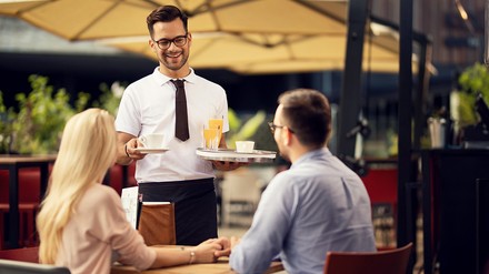 Kellner bedient Gäste im Außenbereich