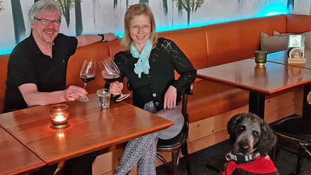Geselliges Paar bei einem Wein im Restaurant mit Hund