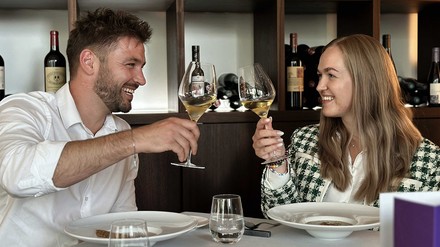 Ein Mann und eine Frau stoßen mit einem Glas Wein in einem Restaurant an