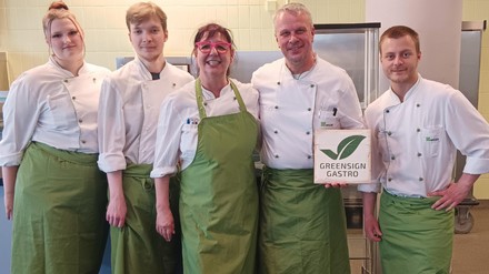 Das Team der Wisag Business Catering Nord-Ost in Kochkleidung mit grünen Schürzen