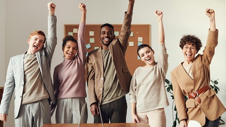 Drei Frauen und zwei Männer strecken motoviert ihre Fäuste in die Höhe