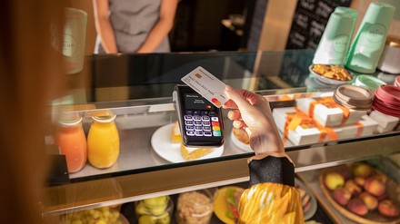 Junge Frau bezahlt in einem Imbiss mit Mastercard