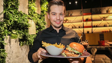 Junger Mannn mit einem Teller mit Burger und Pommes
